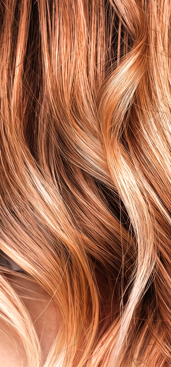 Immagine di una ragazza con capelli mossi, biondi con dei riflessi rossi. Lo sguardo è rivolto verso sinistra